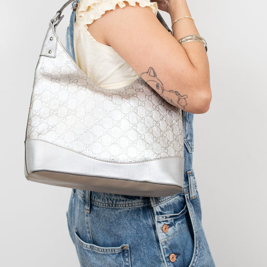 Person holding a textured silver handbag against a plain background