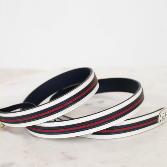 Navy blue, white and red striped belt on a marble surface