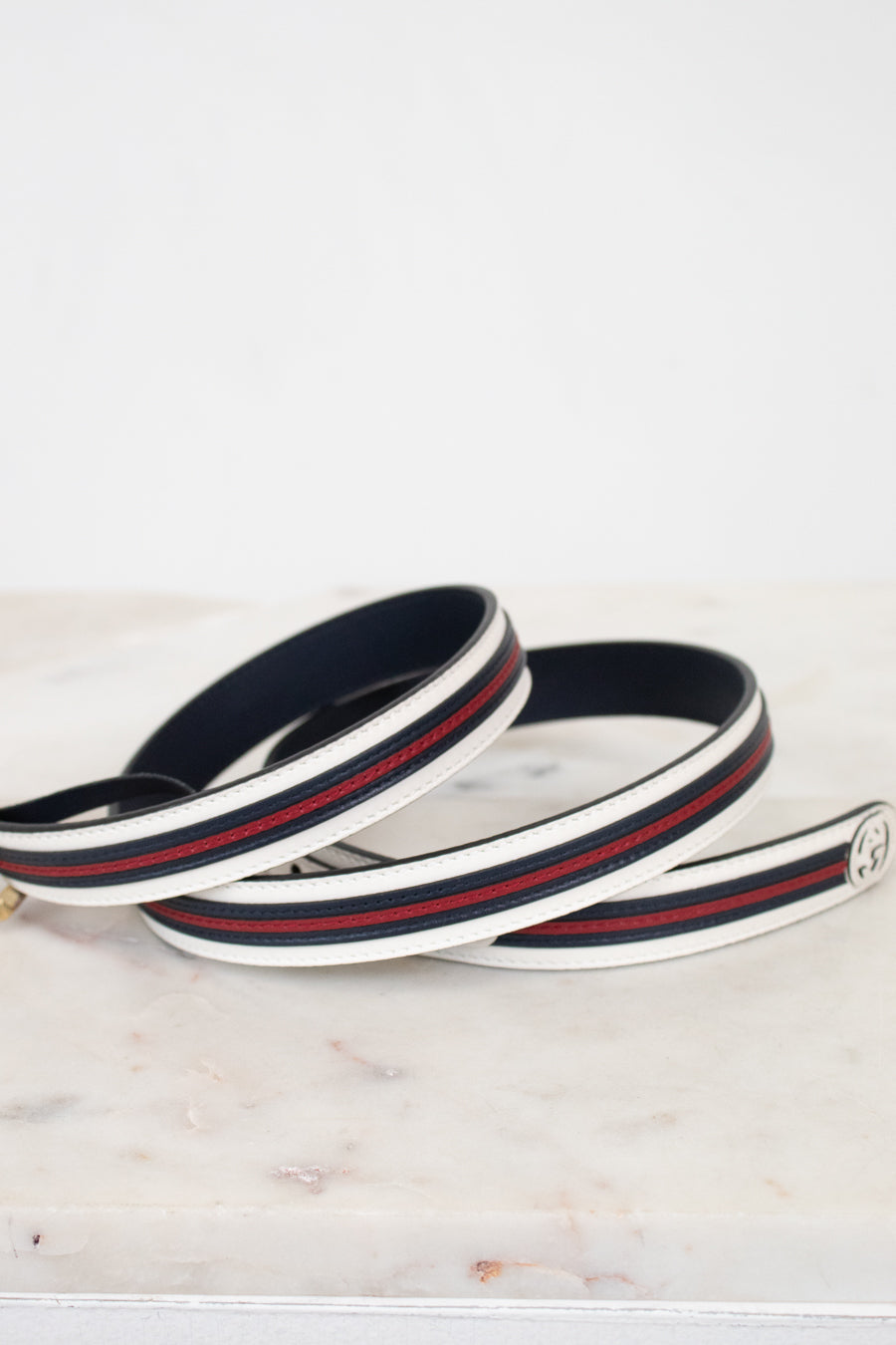 Navy blue, white and red striped belt on a marble surface