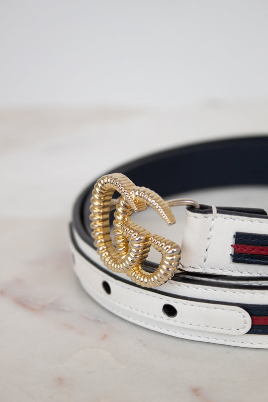 White leather belt with gold buckle on a marble surface