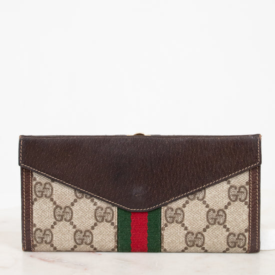 Designer wallet with dark brown leather flap and patterned body on a white background