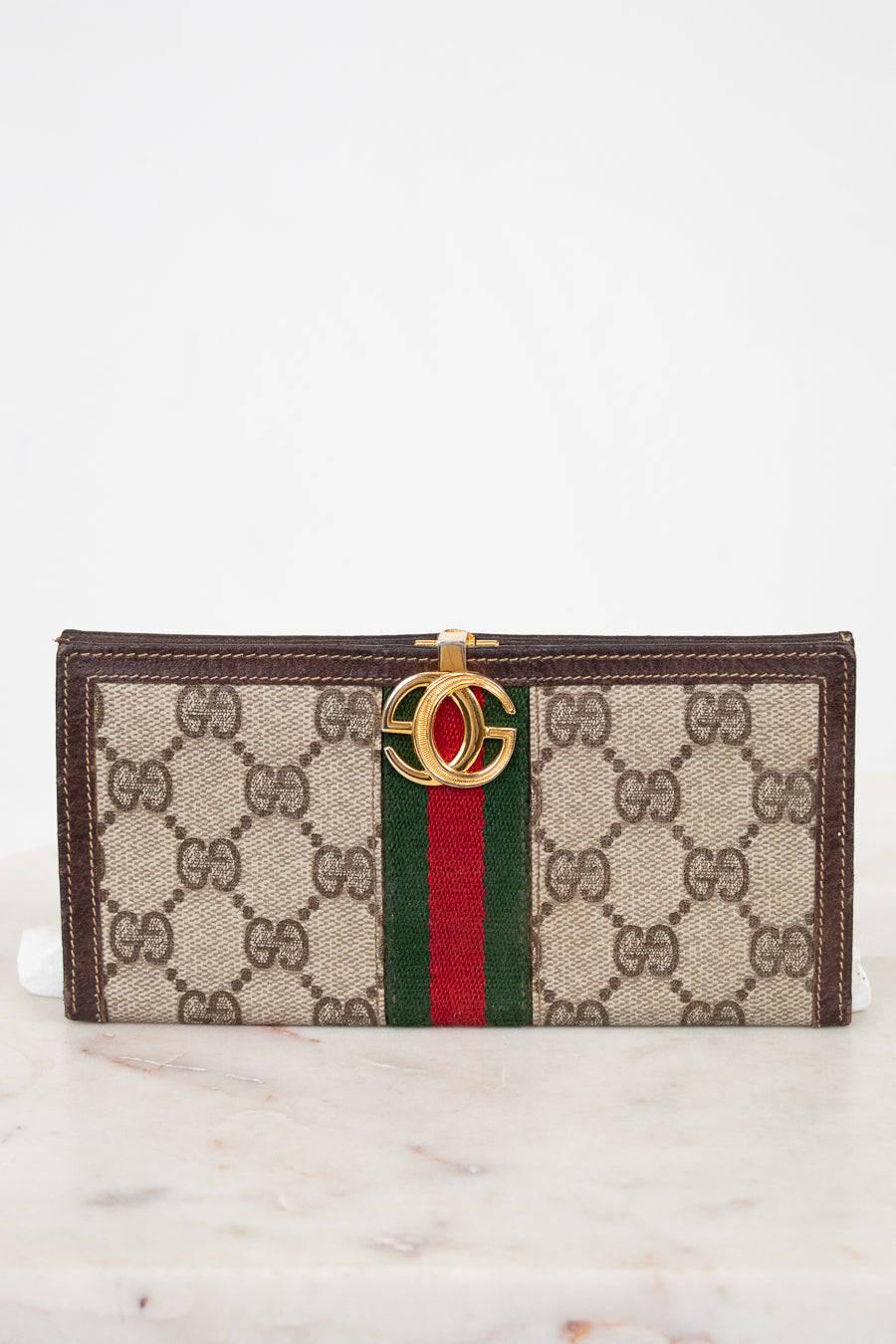 Designer wallet with brand logo and color stripe on a marble surface