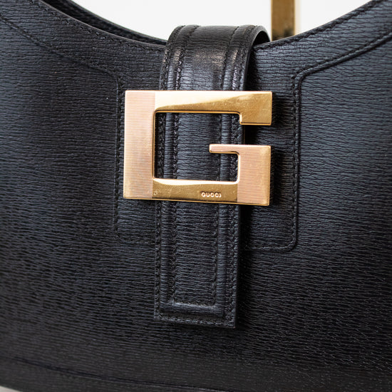 Black handbag with gold buckle on a light background