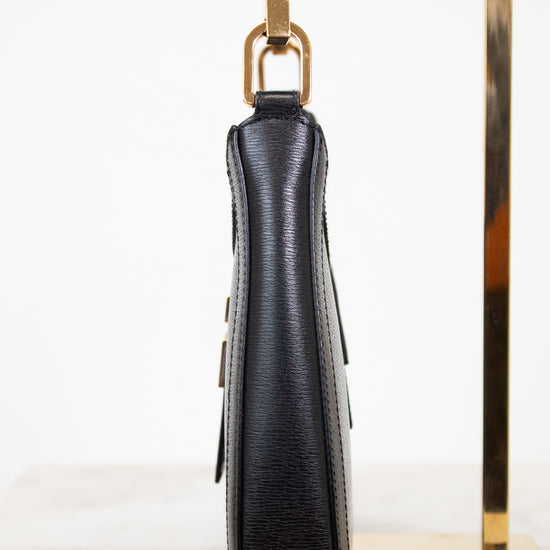 Black textured handbag with gold accents on a white background