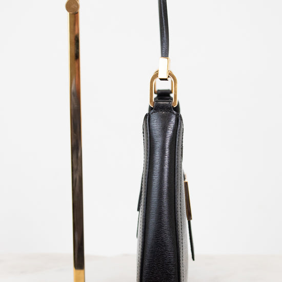 Black leather handbag with gold accents on a white background
