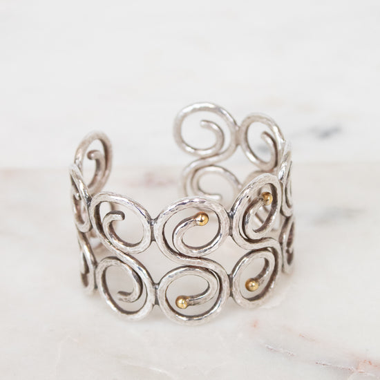 Silver cuff bracelet with intricate designs on a marble surface