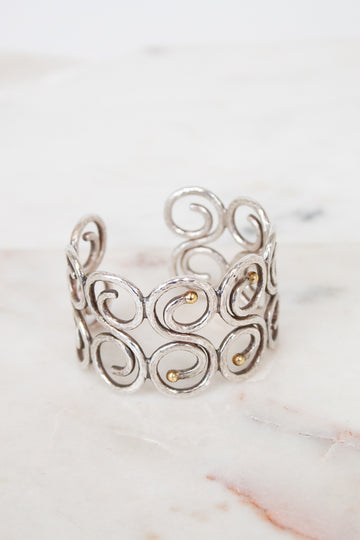 Silver cuff bracelet with intricate designs on a marble surface