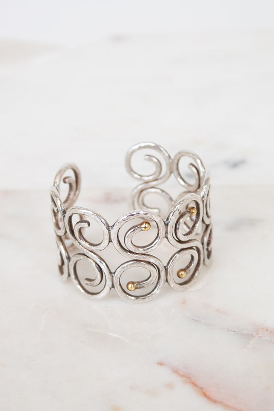Silver cuff bracelet with intricate designs on a marble surface