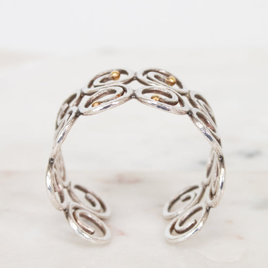 Side view of silver swirl cuff bracelet on white background