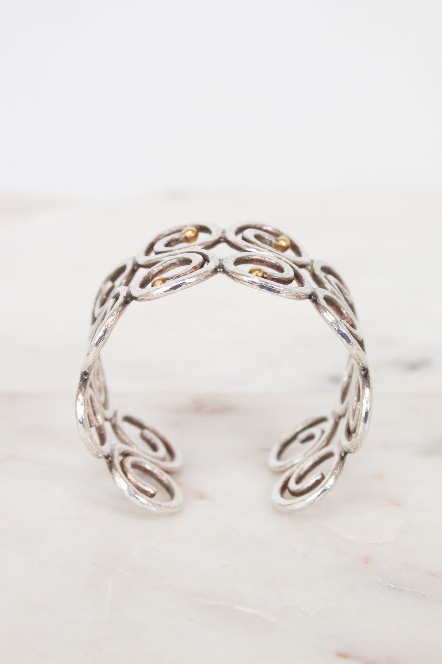 Side view of silver swirl cuff bracelet on white background