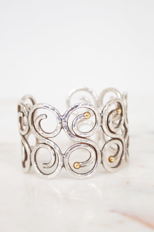 Silver cuff bracelet with gold accents on a white background