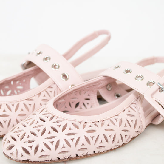 A pair of light pink leather ballet flats with laser-cut geometric star patterns and silver-tone metal eyelets on the straps, displayed on a light marble surface against a white background.