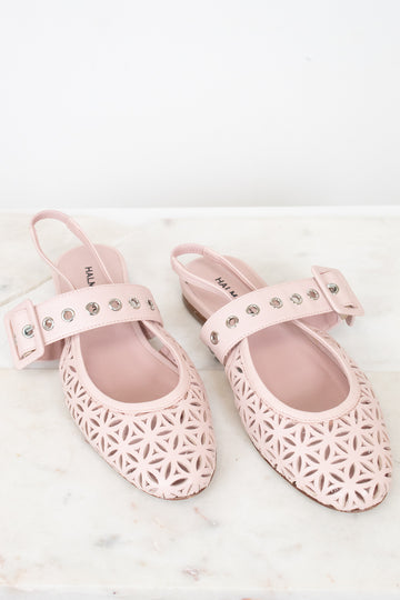 A pair of light pink slingback flats with geometric cutout detailing on the toe and side, featuring a decorative strap with silver studs on a white marble surface.