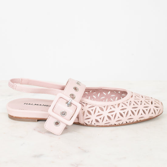 A single light pink flat shoe with a geometric laser-cut pattern on the toe and a matching strap with a buckle closure, shown on a white marble surface against a white background.