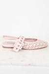 A single light pink flat shoe with a geometric laser-cut pattern on the toe and a matching strap with a buckle closure, shown on a white marble surface against a white background.