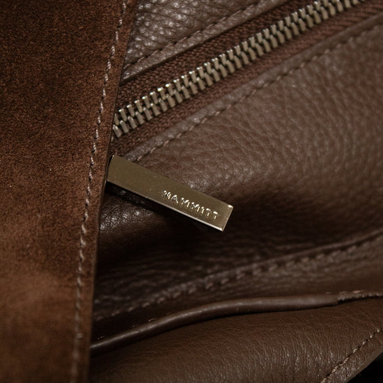 Close-up of a brown leather bag with a visible brand logo.