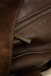Close-up of a brown leather bag with a visible brand logo.