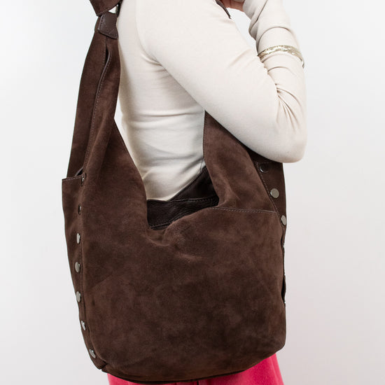 Person wearing a brown hobo bag on a white background