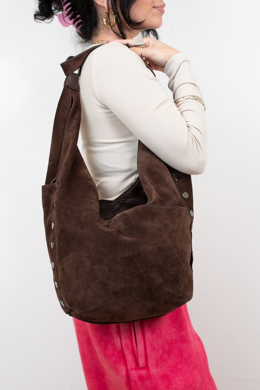 Person wearing a brown hobo bag on a white background