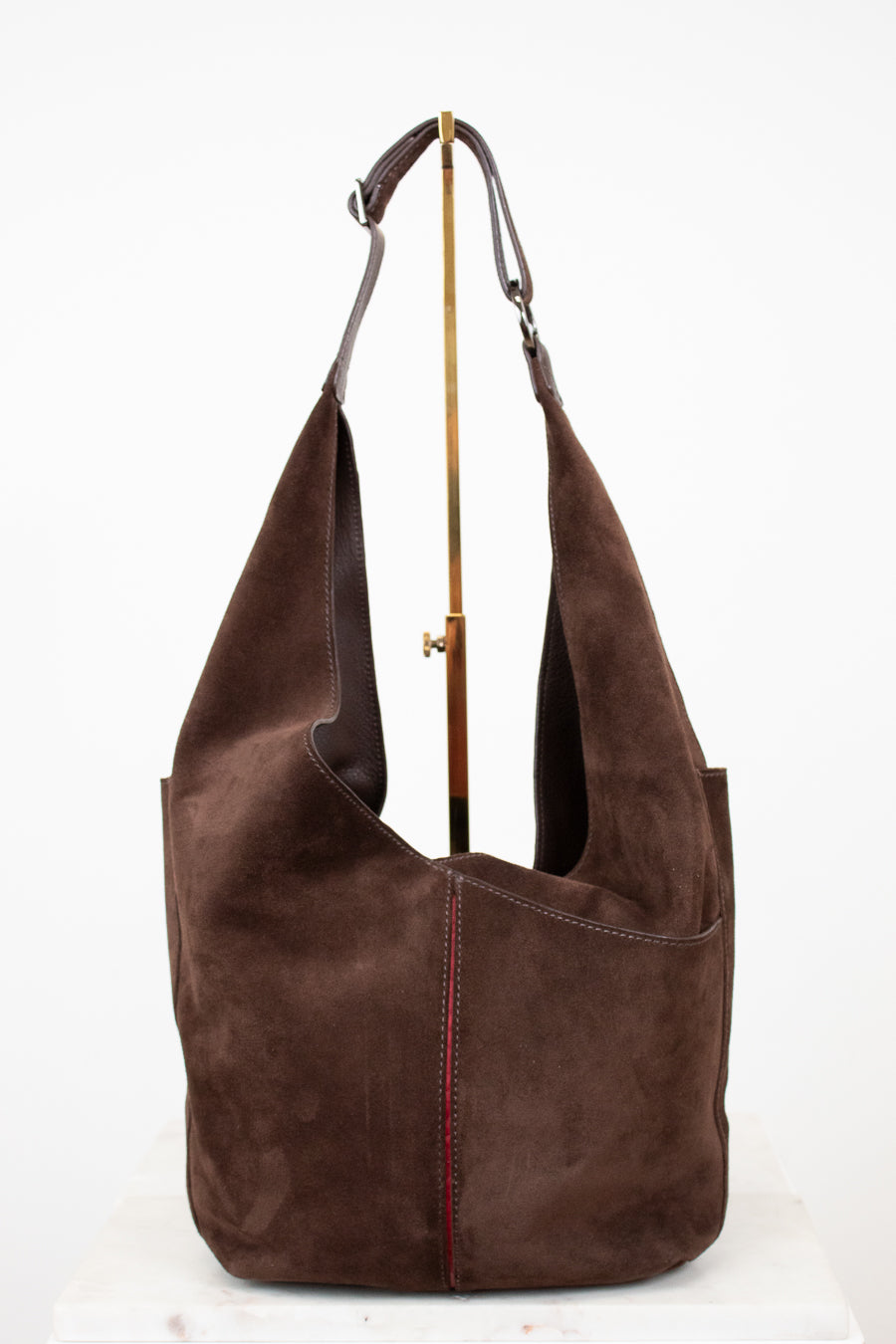 Brown suede handbag with a strap on a white background