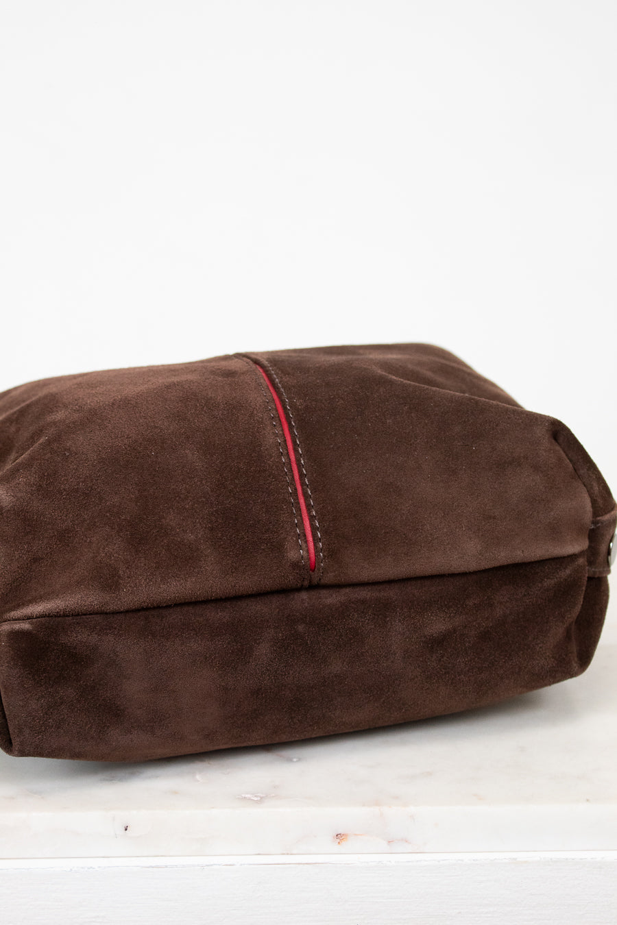 Brown suede to hobo bag with red stitching on a white background