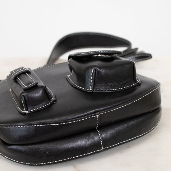 Black leather bag with buckle details on a marble surface