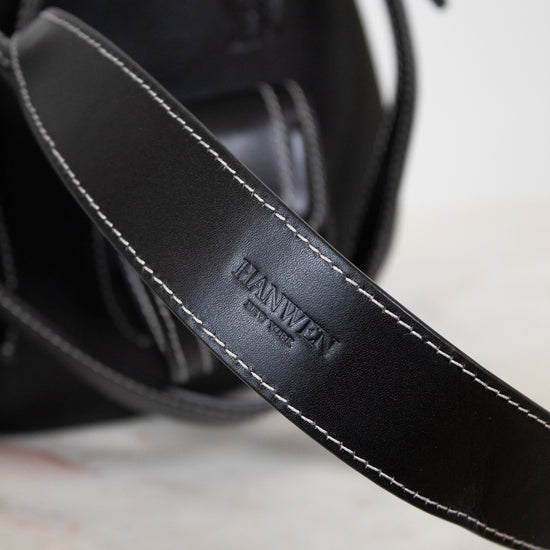 Close-up of a black leather strap with 'HANWEN' branding on a marble surface.