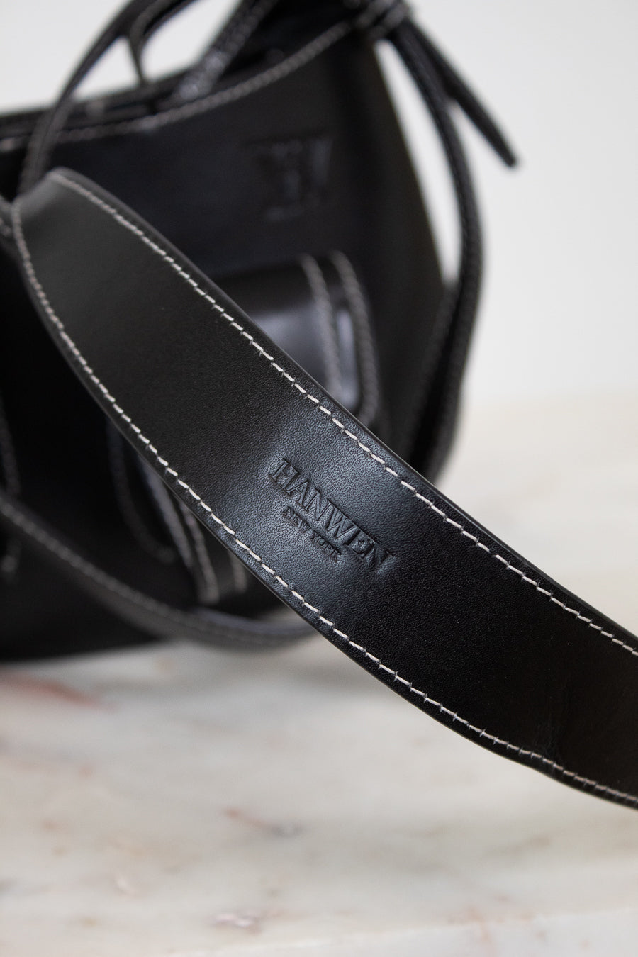 Close-up of a black leather strap with 'HANWEN' branding on a marble surface.