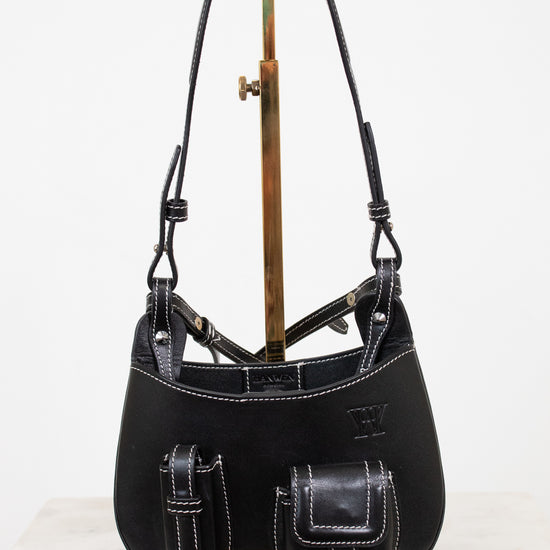 Black leather handbag on a stand against a white background