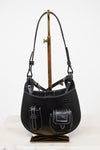 Black leather handbag on a stand against a white background