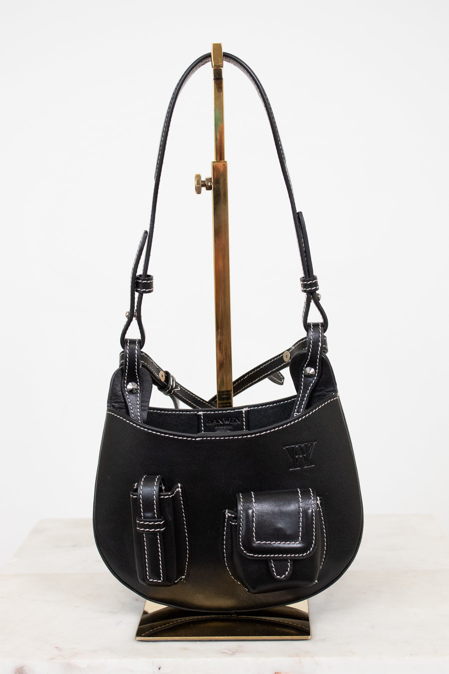 Black leather handbag on a stand against a white background