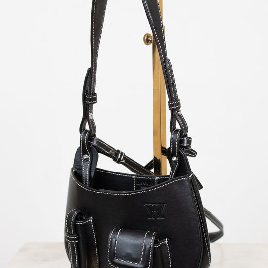Black leather bag on a wooden stand against a white background