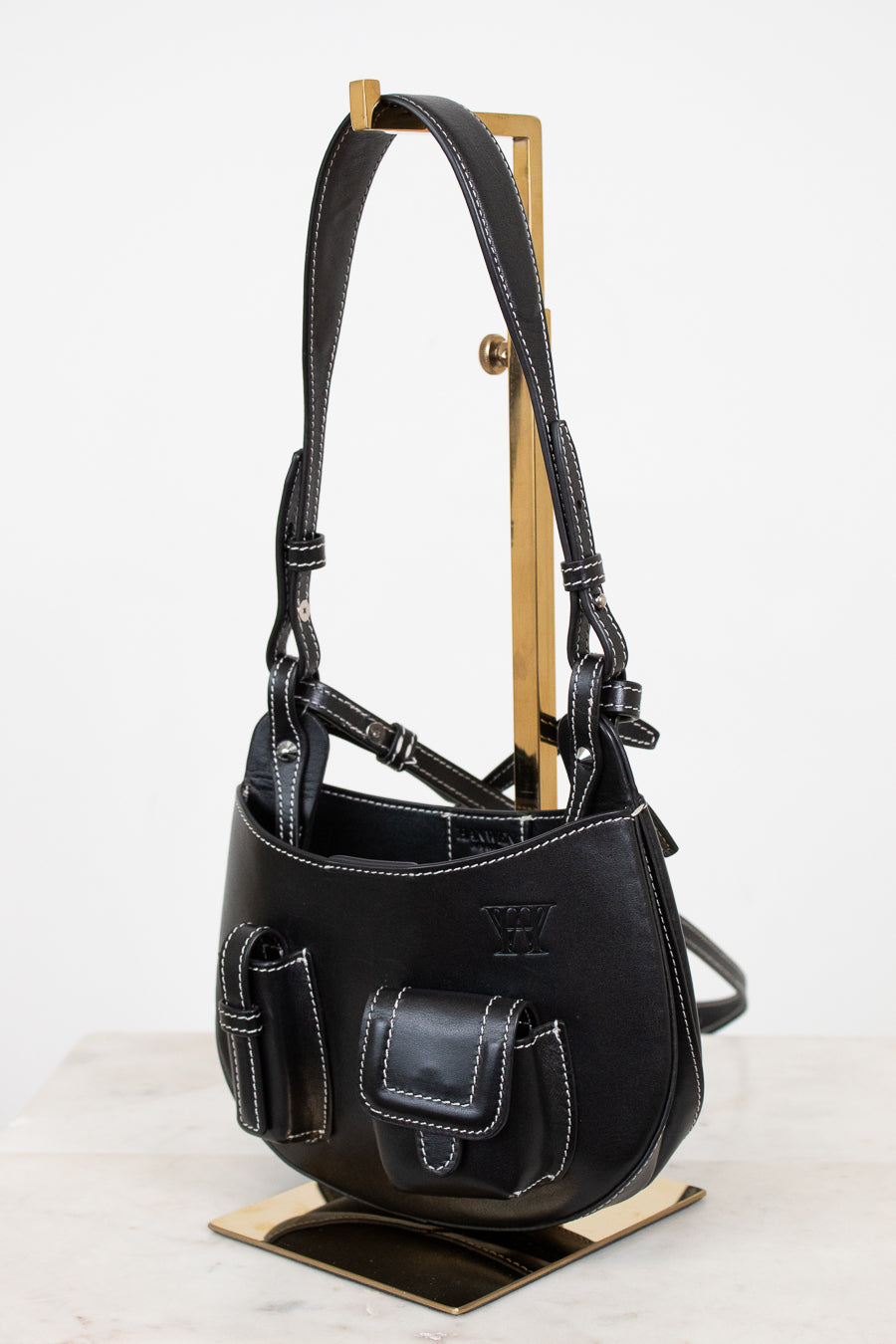 Black leather bag on a wooden stand against a white background