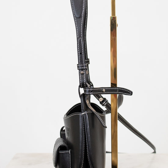 Black handbag on a gold stand against a white background