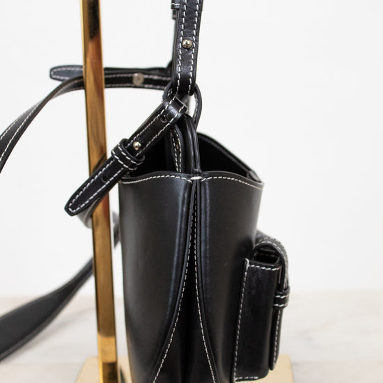 Black handbag on a metallic stand with a white background