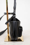 Black handbag on a metallic stand with a white background