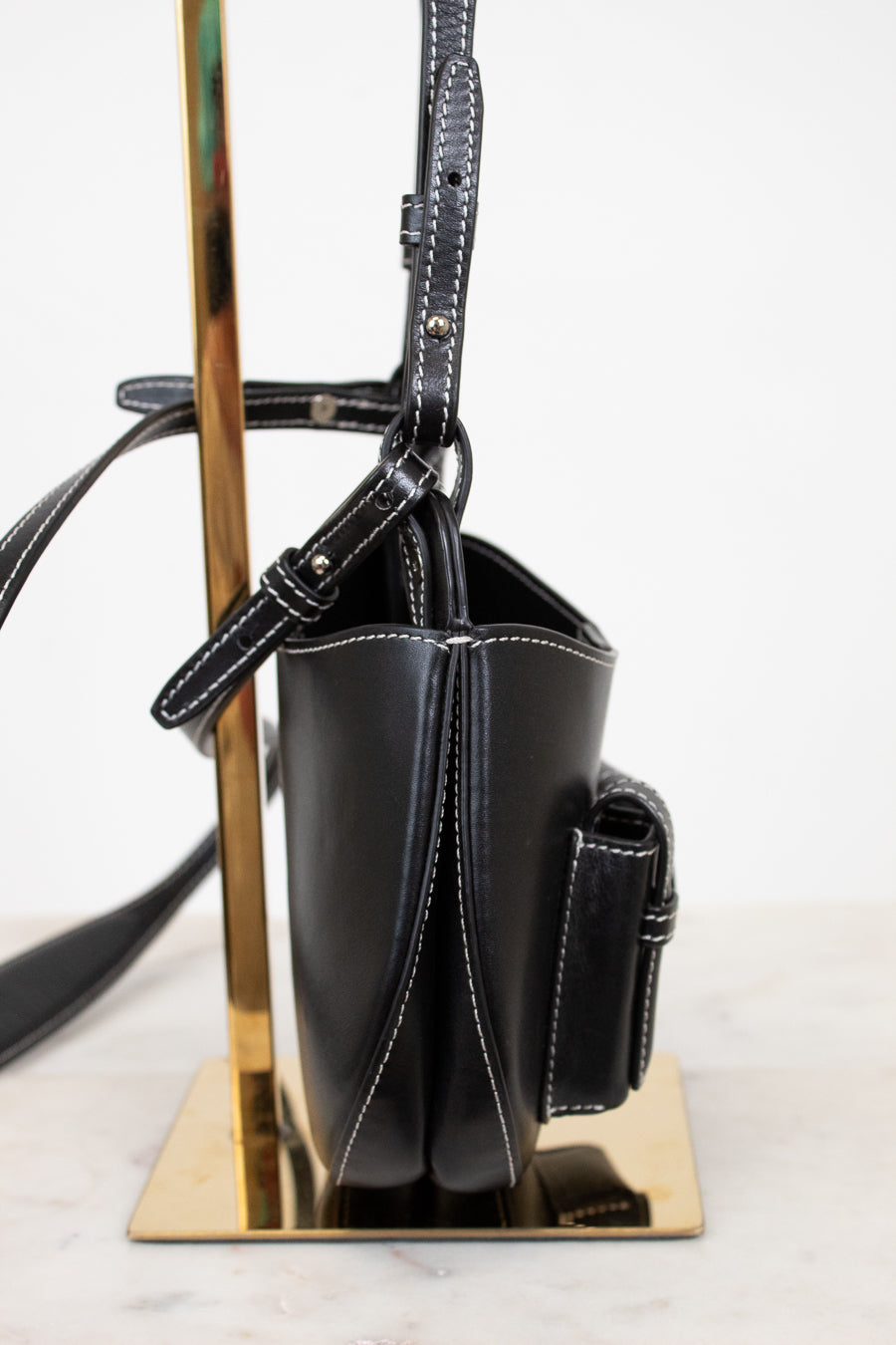 Black handbag on a metallic stand with a white background