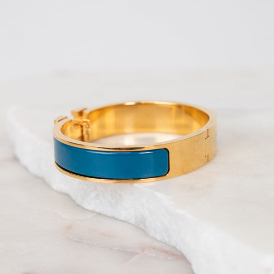 Gold bracelet with a blue band on a white marble surface