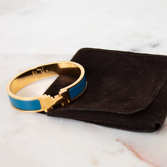 Gold and blue bracelet on a black pouch against a marble background
