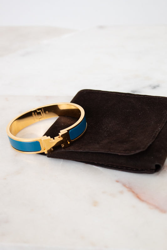 Gold and blue bracelet on a black pouch against a marble background