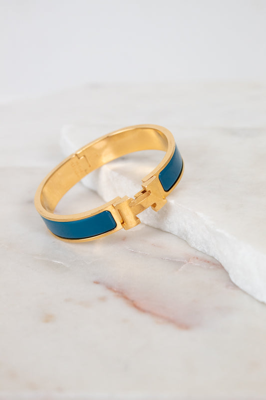 Teal and gold bracelet with H clasp on white background