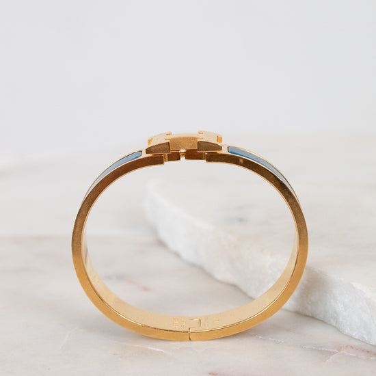 Gold bracelet on a marble surface with a light gray background