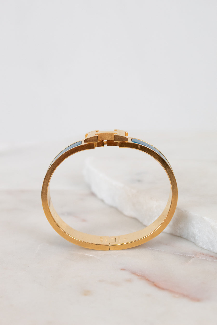 Gold bracelet on a marble surface with a light gray background