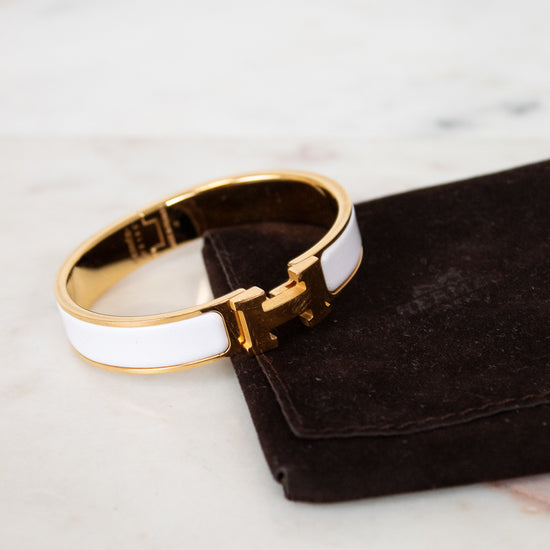 Gold and white bracelet on a black jewelry pouch with a marble background