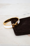 Gold and white bracelet on a black jewelry pouch with a marble background