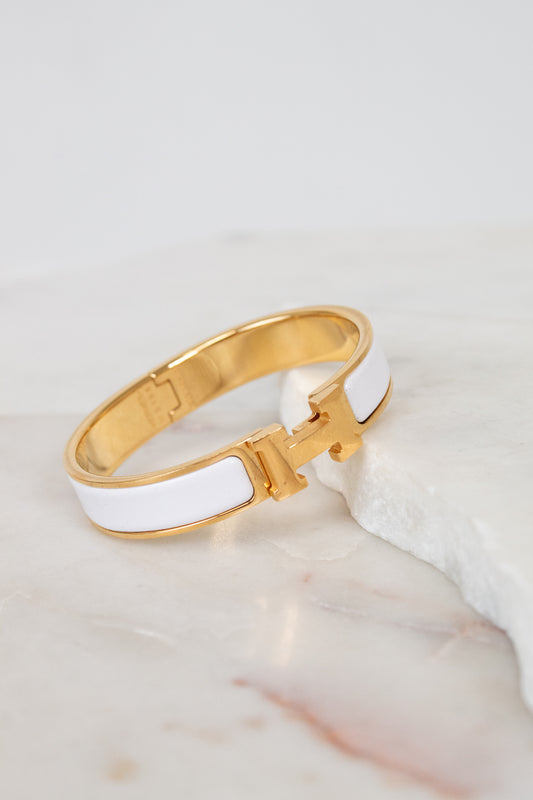 Gold and white bracelet on a marble surface