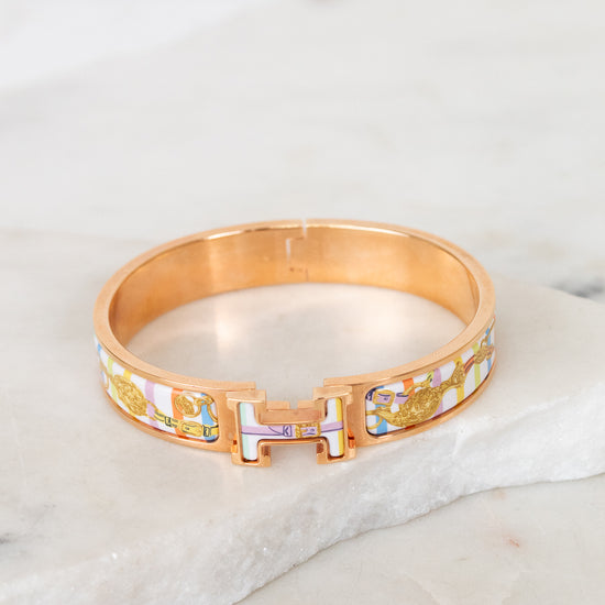 Rose gold bracelet with multicolor letters on a marble surface