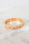 Rose gold bracelet with multicolor letters on a marble surface