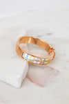 Rose gold bracelet with colorful pattern on a marble surface