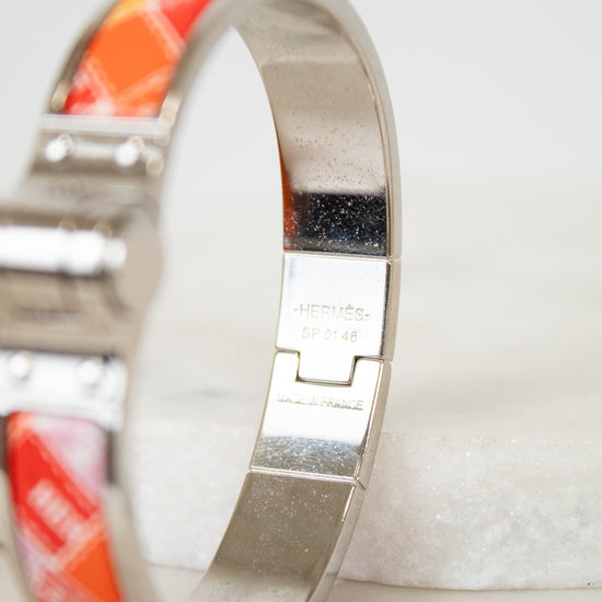 Silver bracelet with red and white pattern on a light background